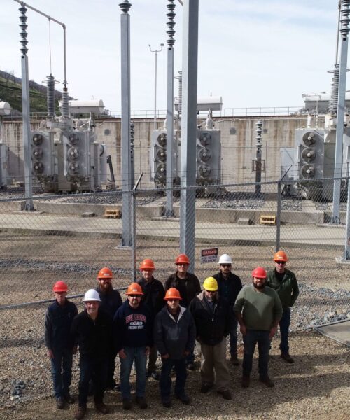 KRCD Hydropower Plant team standing together in front of electrical yard