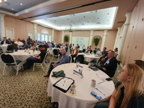 Photo of approximately 60 people listening to presentations